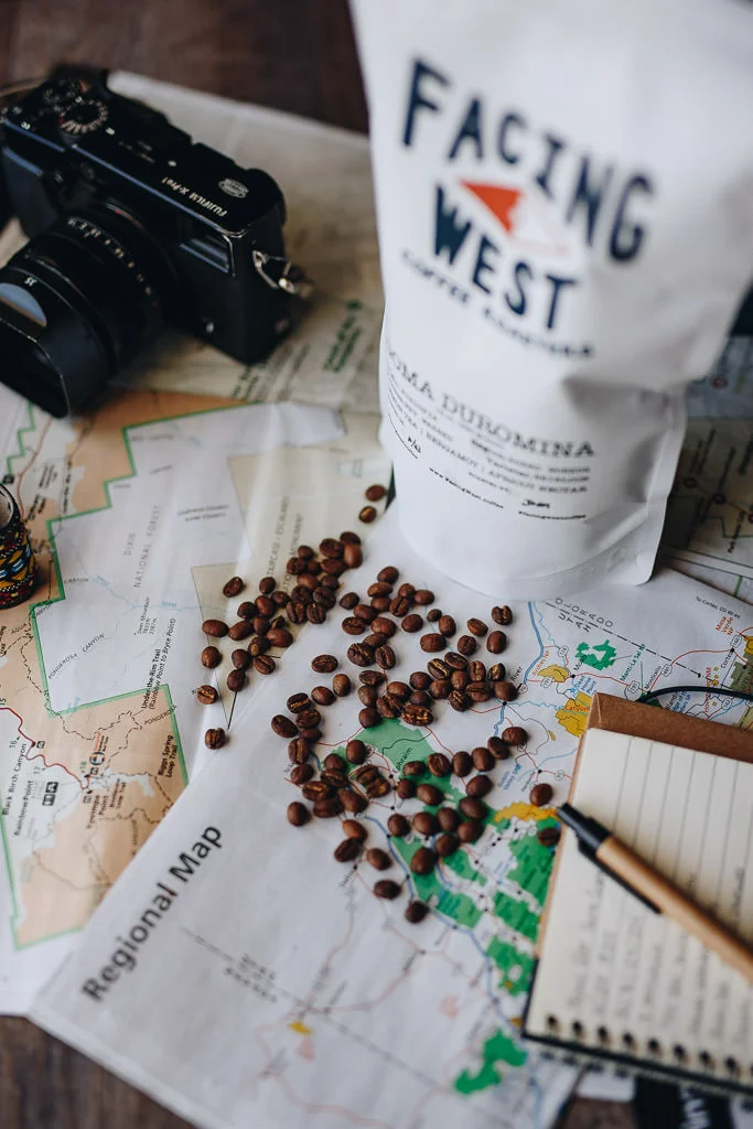 Whole bean coffee on maps with camera and notebook
