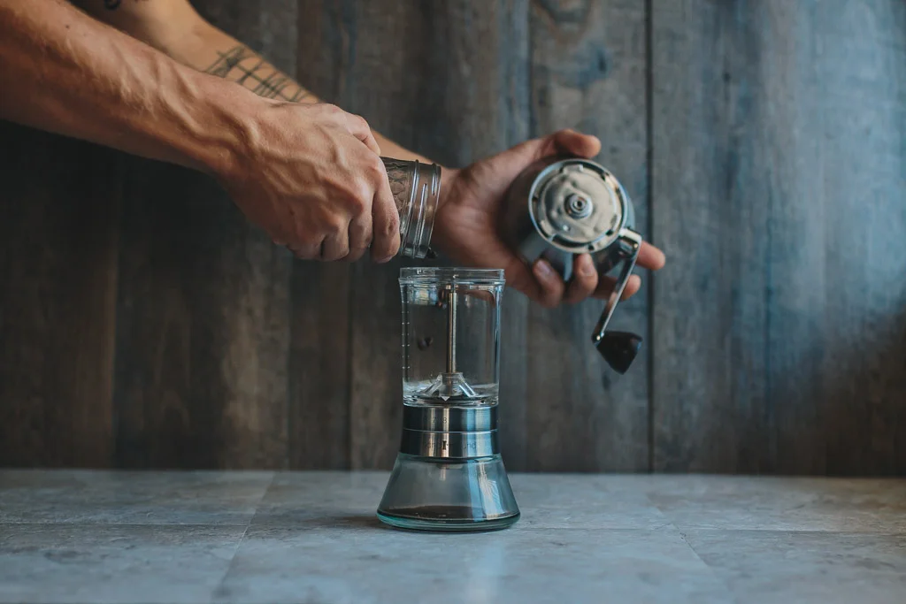 Adding whole bean coffee to handgroud hand grinder