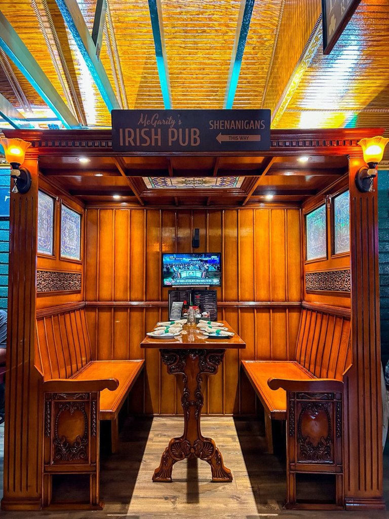 Rich wood-paneled dining booth with a stained-glass ceiling and Irish pub details at McGarity’s.