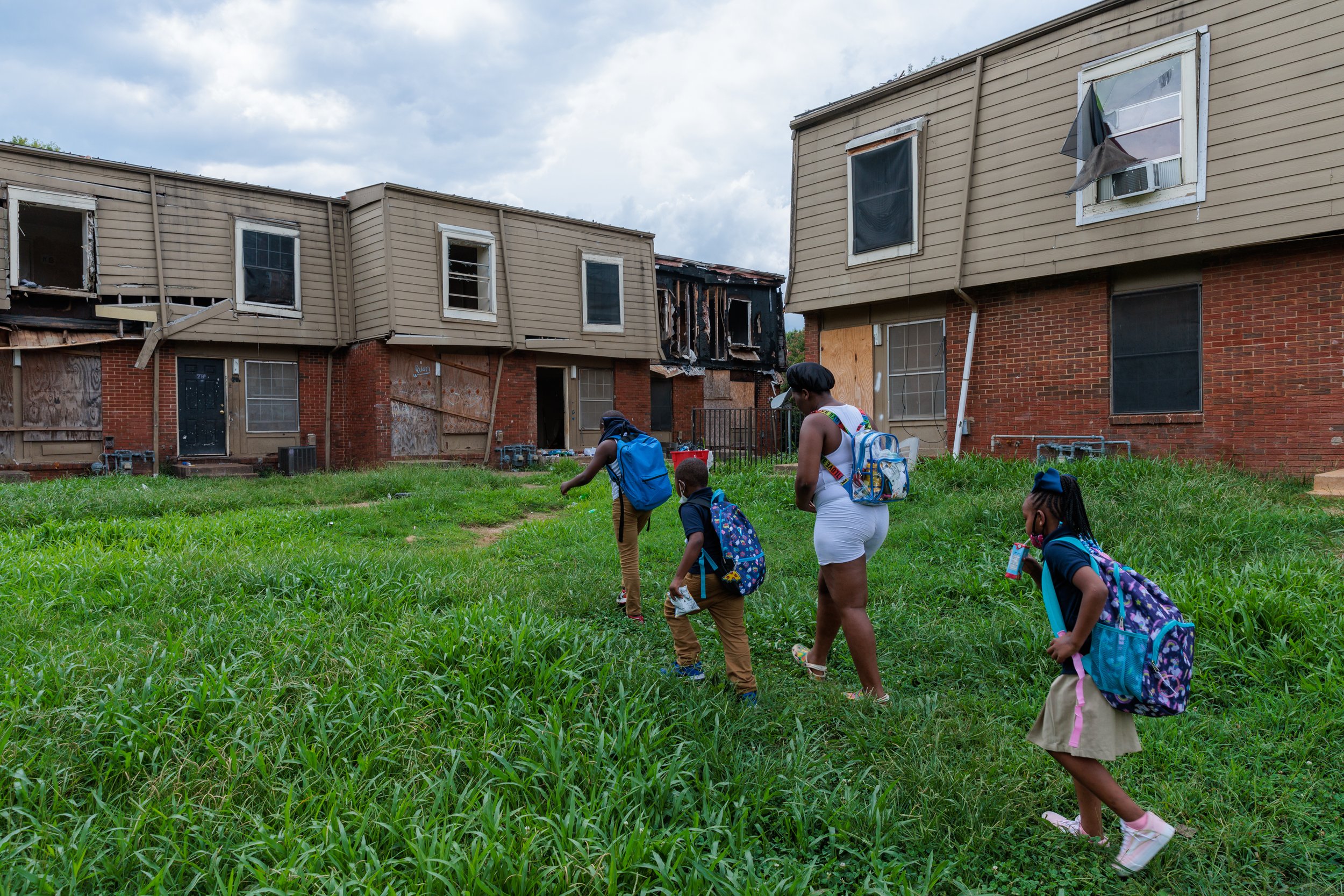  A family living in the Forest Cove Apartments in Atlanta walks to their home from the children's bus stop in August 2022. 