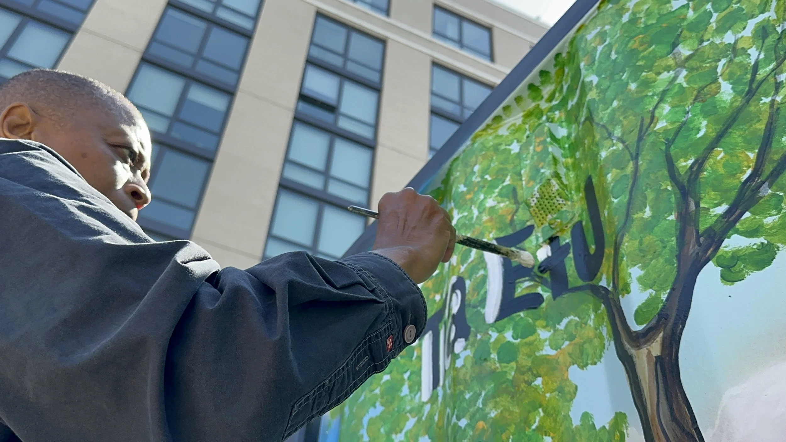 Tia signing her name on the mural