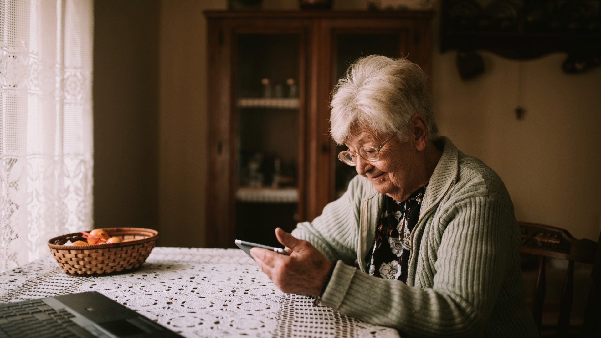 Woman on phone at dining table in house.