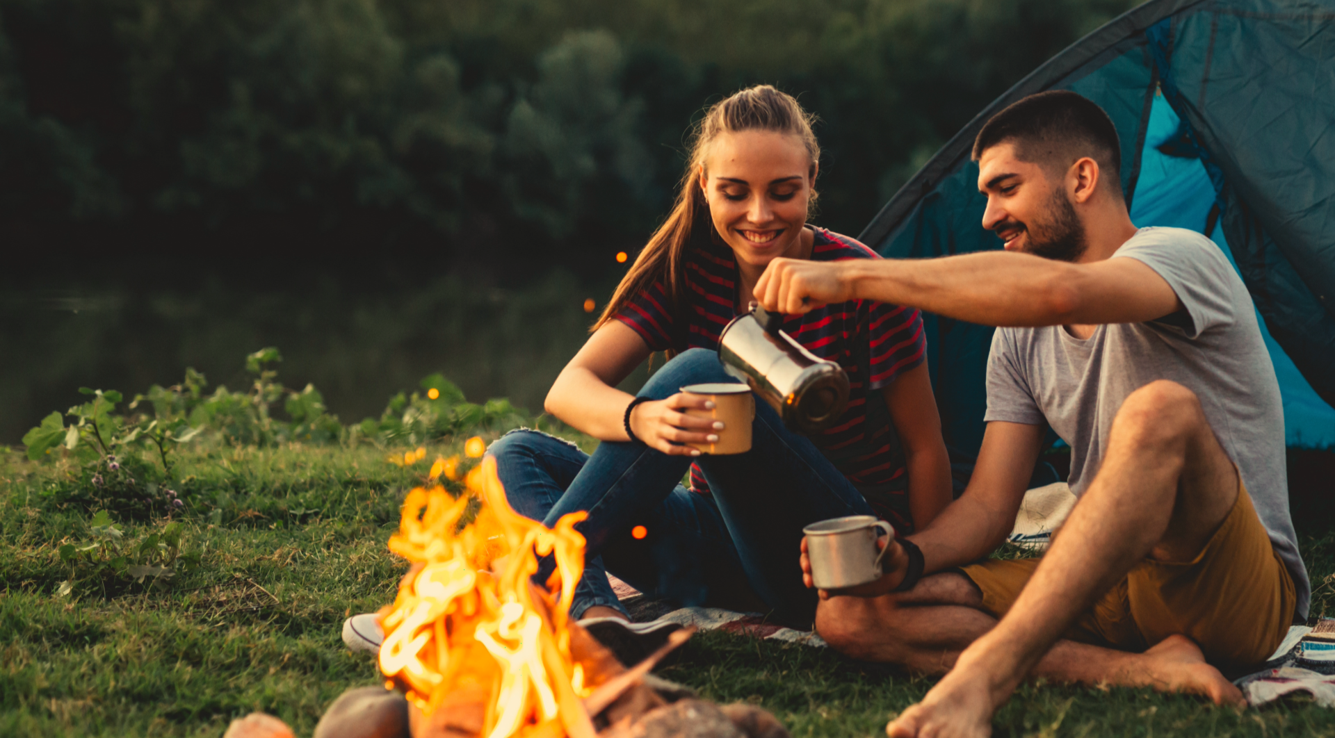 Two people sharing coffee by a fire