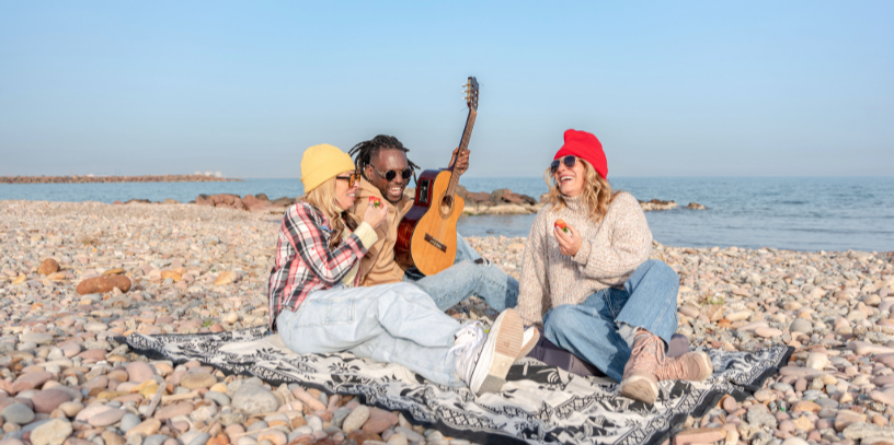 Three people sitting on a beach laughing