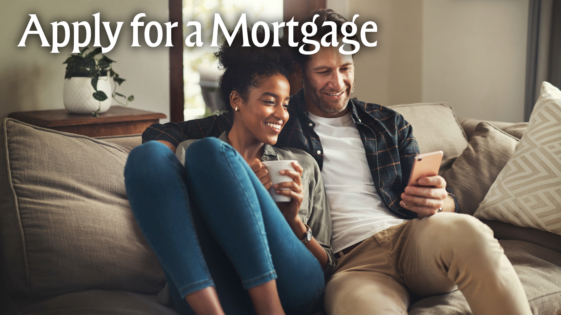 Apply for a mortgage. Couple sitting on couch looking at phone.