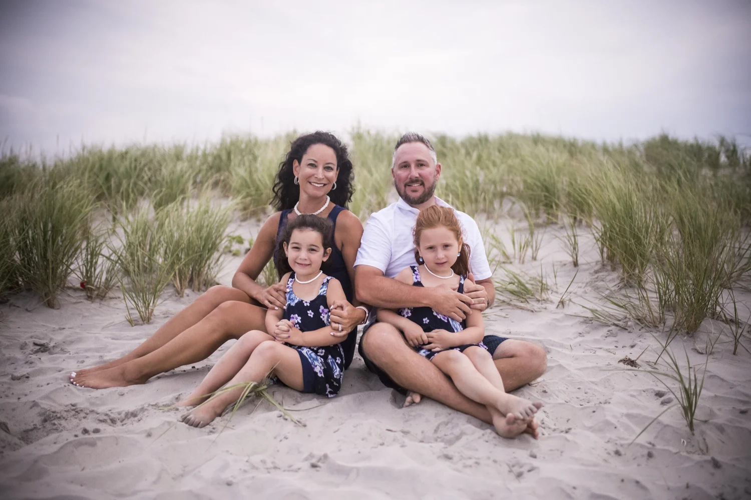 A family sitting together on the beach dunes