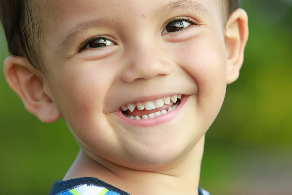 This is a picture of a smiling young boy with baby teeth.
