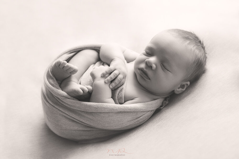 Black and white image of newborn baby wrapped by NP Photography