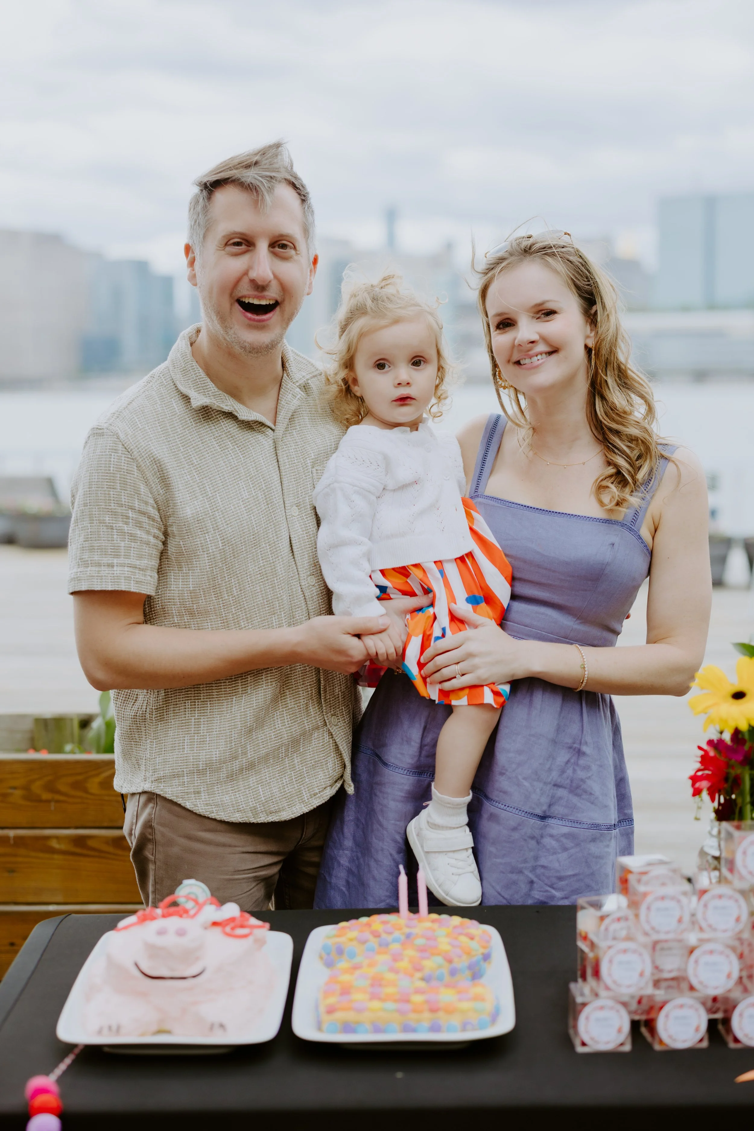 Family celebrating child's birthday outdoors with birthday cake and decorations.