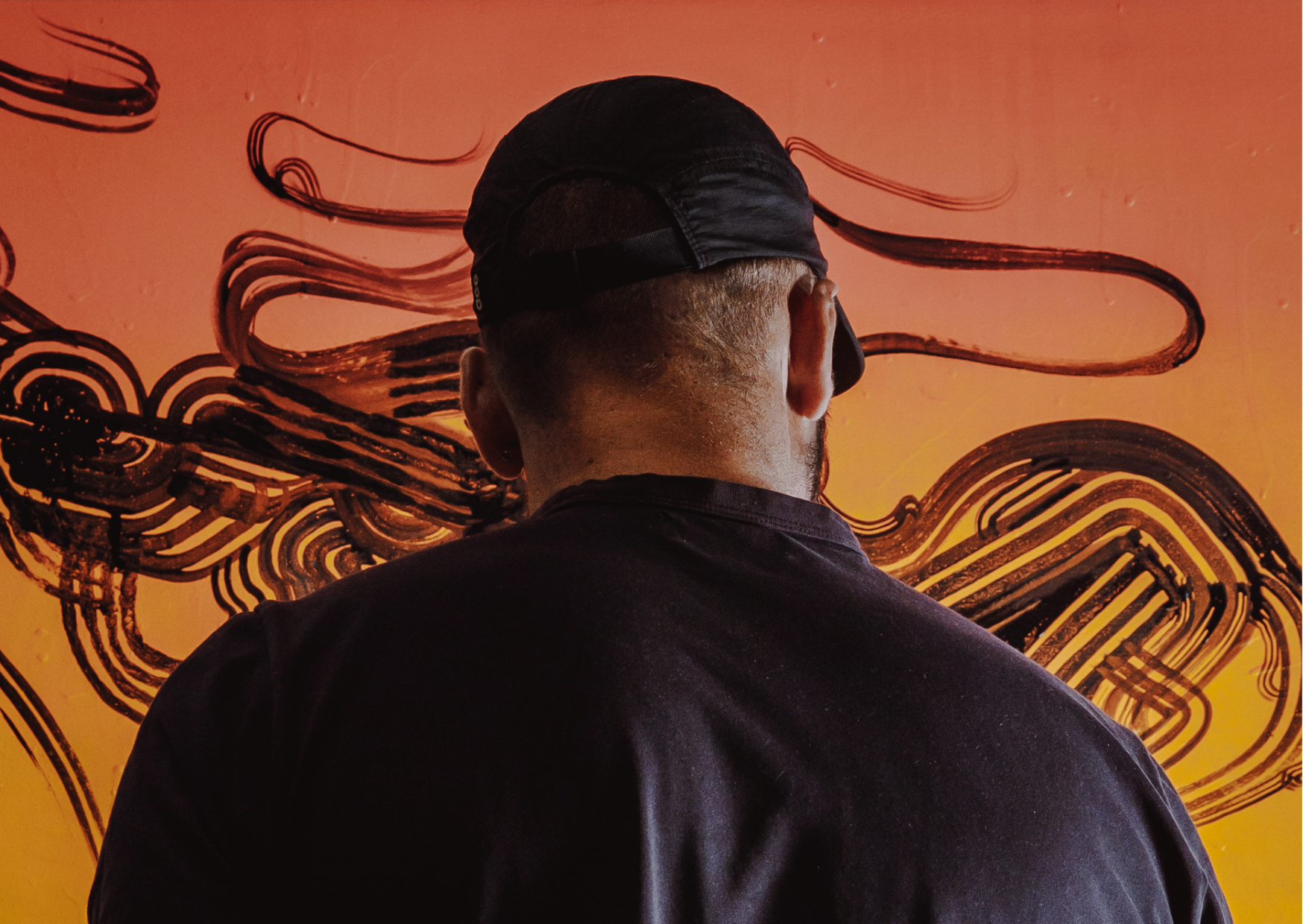 Photograph of the back of the artist, in front of highly graphic custom artwork created for.  Melbourne Graffiti Artist Bailer's opening night for their solo exhibition titled 'Mixed Messages'.