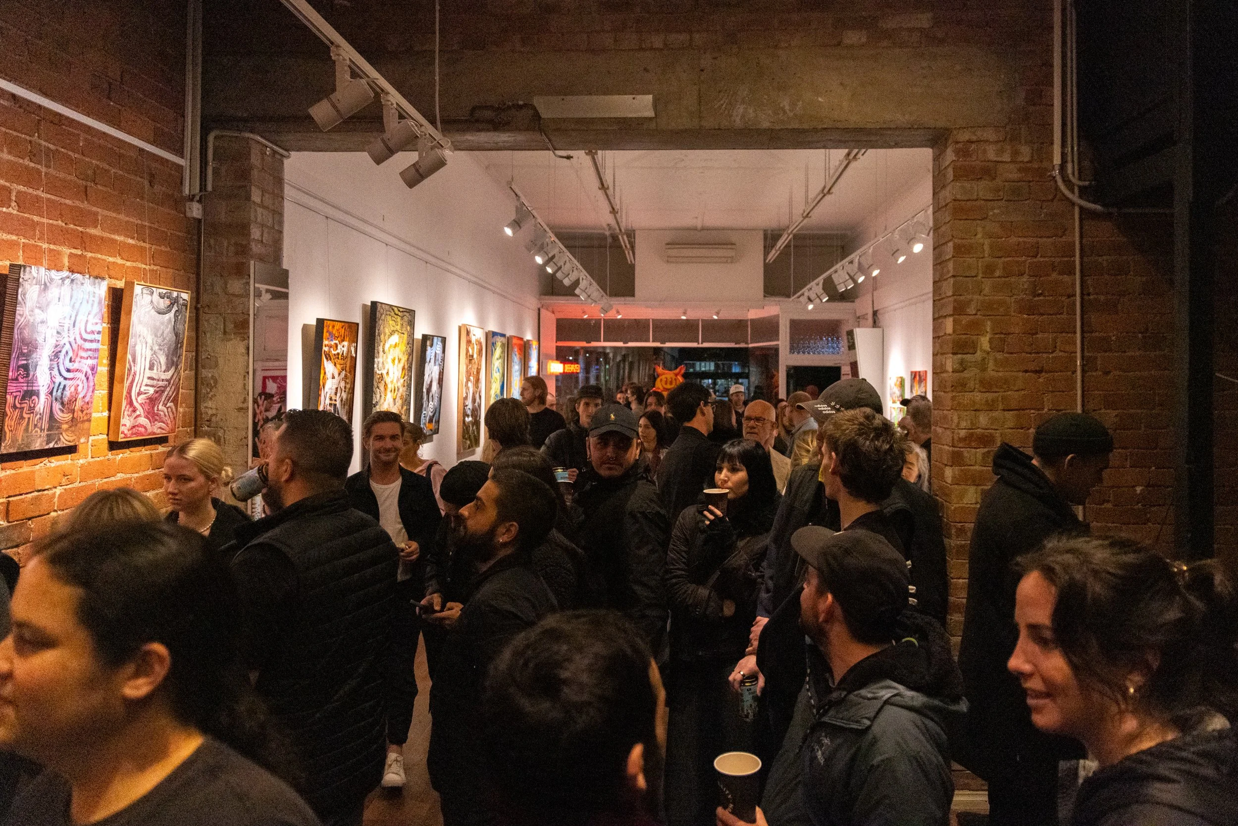 Photograph of full house of gallery visitors at Let's Pretend Gallery. The image is from Melbourne Graffiti Artist Bailer's opening night for their solo exhibition titled 'Mixed Messages'.