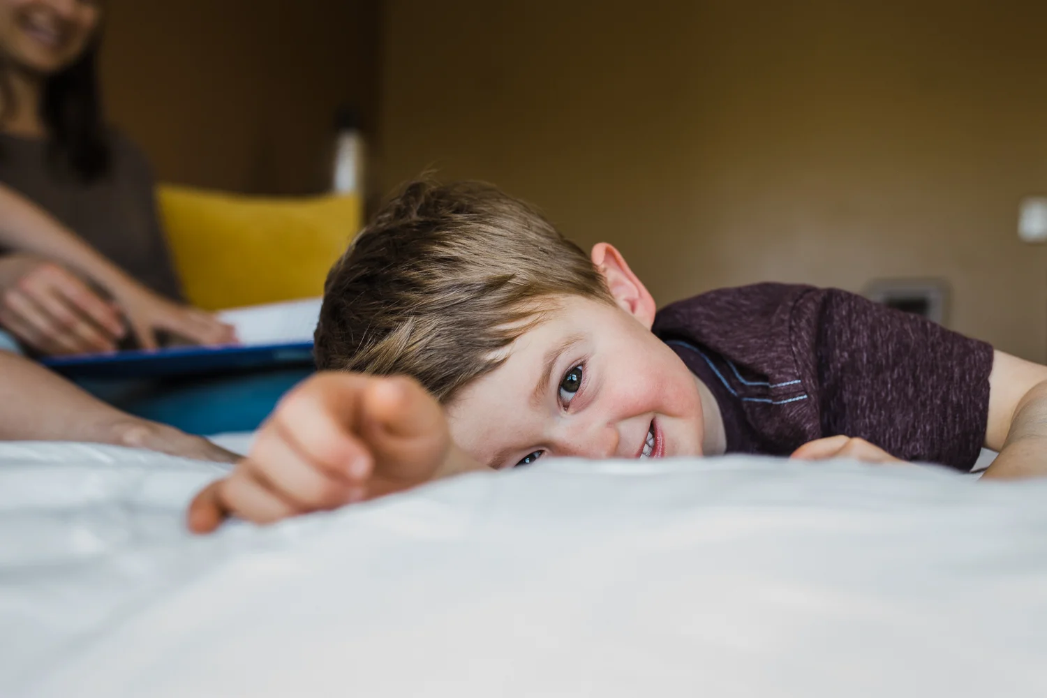 3 year old boy smiling and laying on parent's bed - san francisco family photography