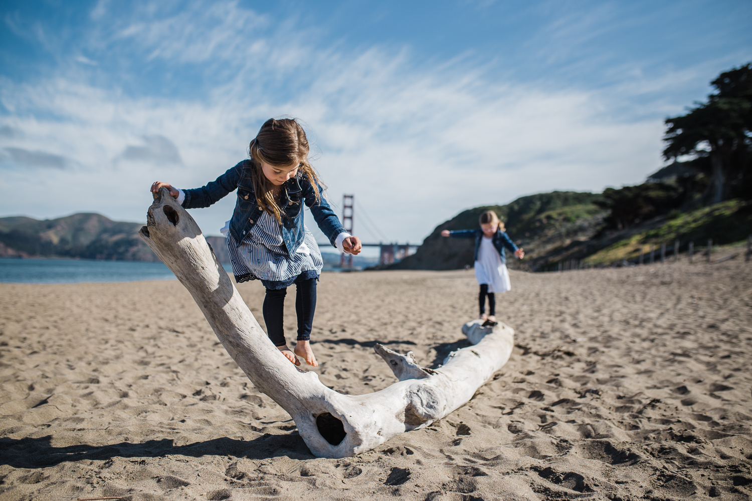 five year old sisters playing on driftwood together on Baker beach {San Francisco Family Photographer}