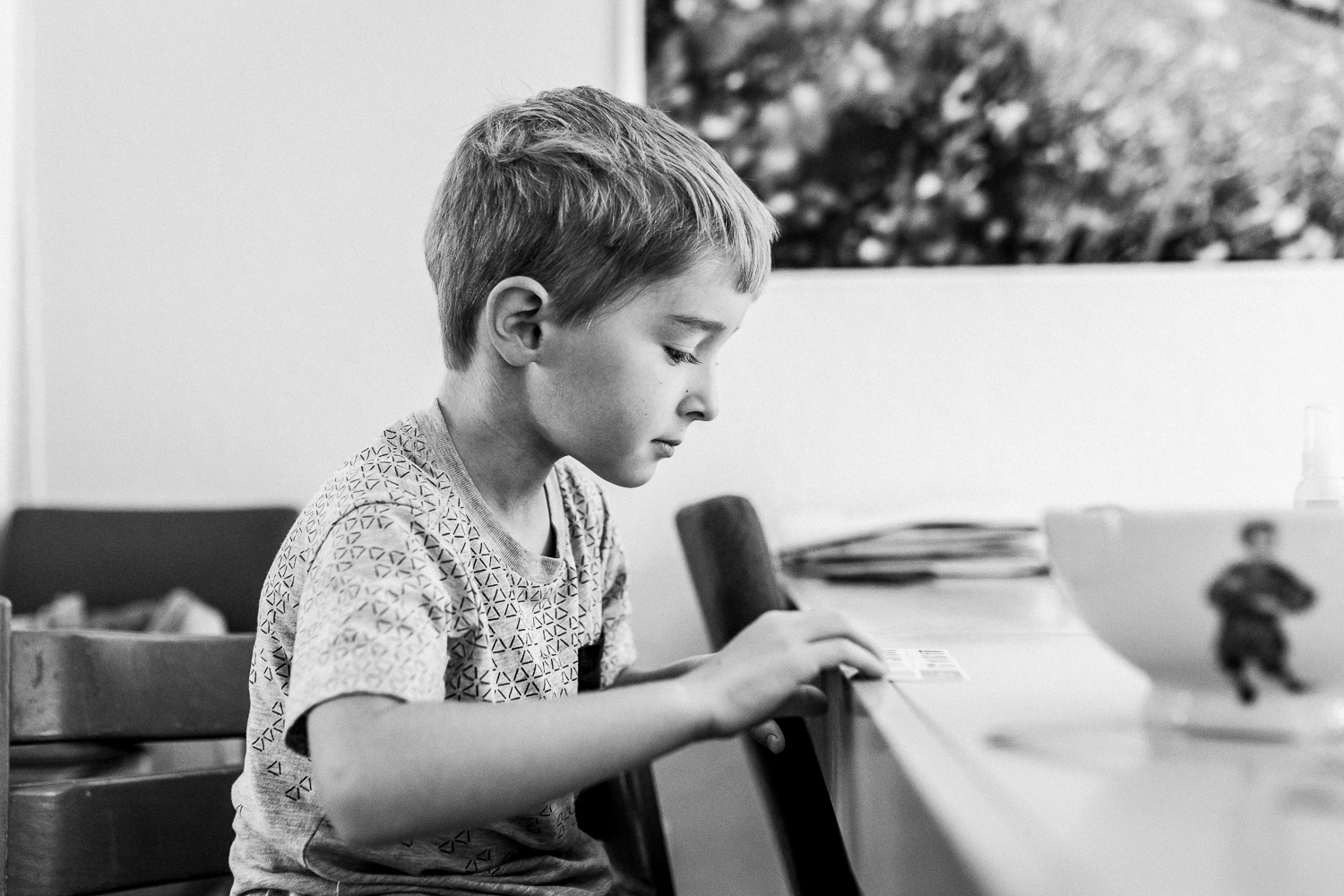 five year old boy sitting at the kitchen table looking at a paper {San Francisco lifestyle Family Photographer}