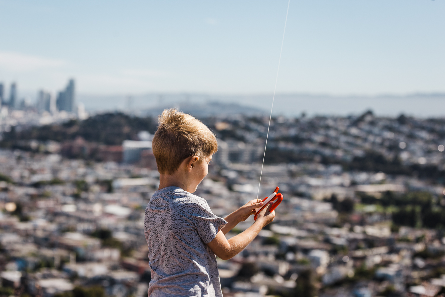 five year old little boy holding his kite with a view of the city in the background {San Francisco lifestyle Family Photographer}