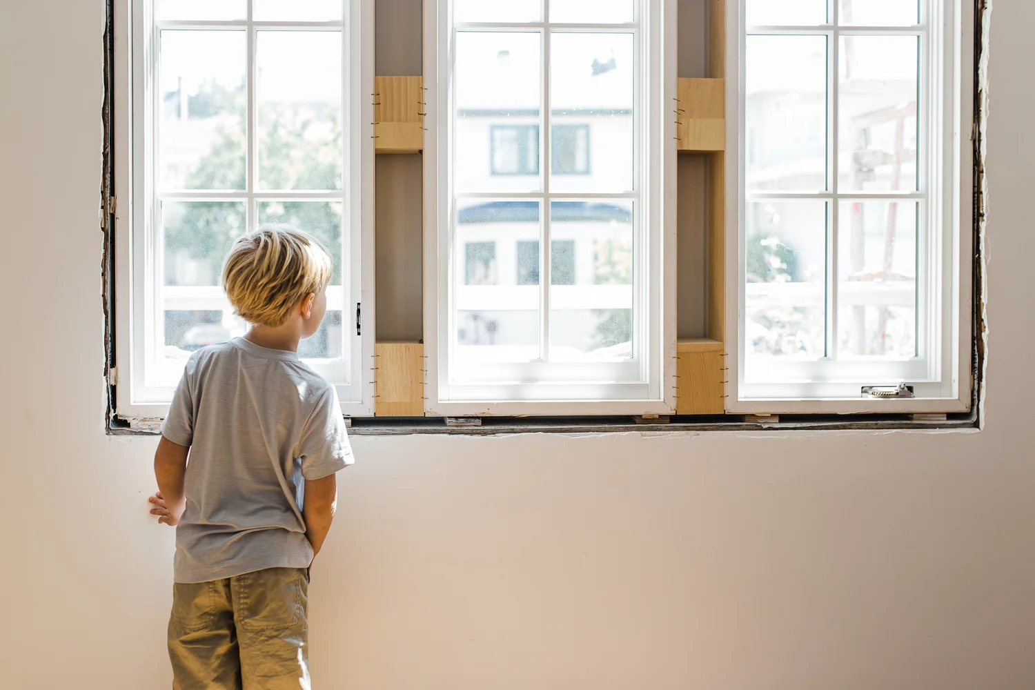 a five year old boy looking out the window of his bedroom still under construction {East Bay Family Photographer}