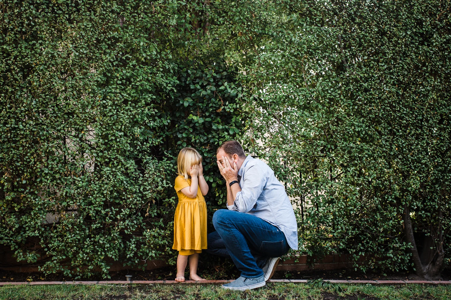 father and three year old daughter playing hide and seek in the bushes waiting for mom {Oakland in-home lifestyle Family Photographer}