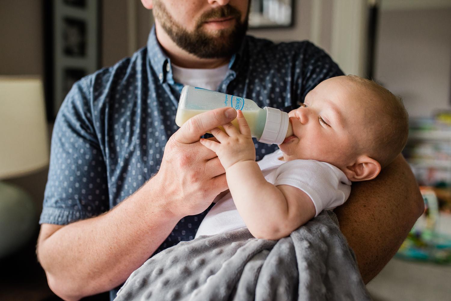 candid moment - Dad holding and giving his newborn baby boy a bottle {San Francisco in-home lifestyle newborn photographer}
