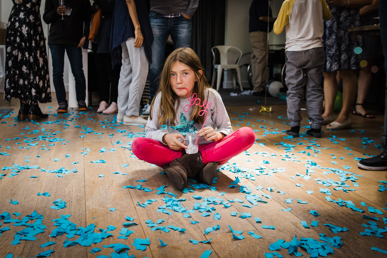A girl sitting on the floor in the middle of blue confetti after a gender reveal party  {San Francisco Family Photographer}