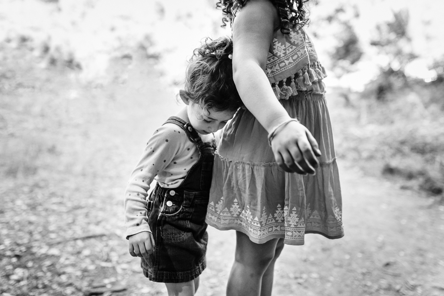 black and white profiles of two sisters standing next to each other with one leaning on the other’s back {Oakland Family Photographer}
