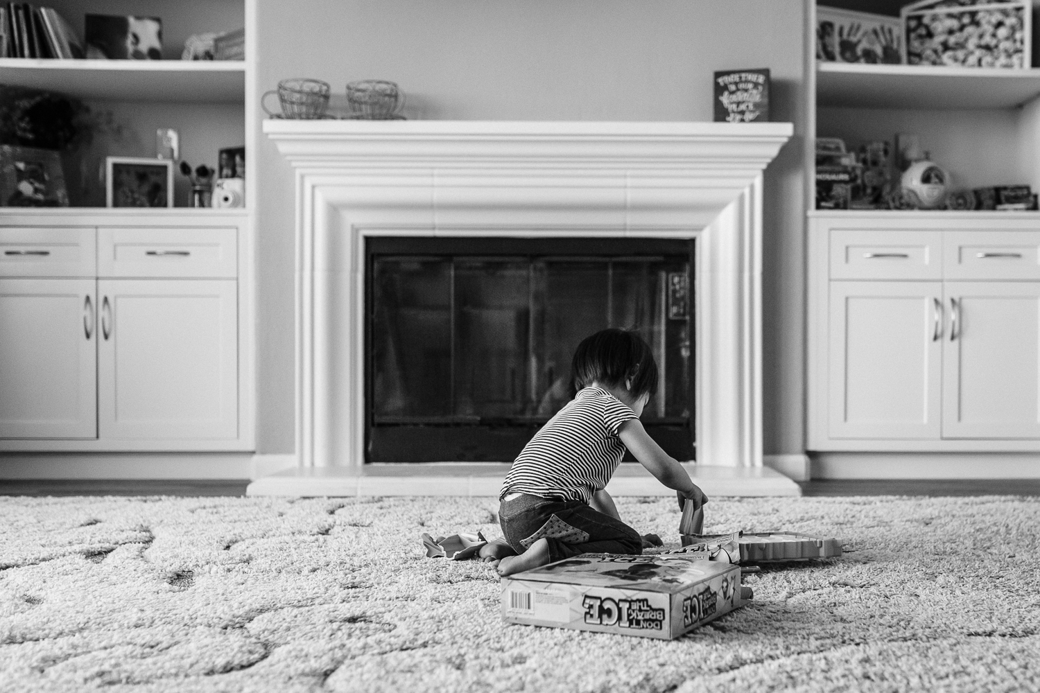 little girl sitting in front of a fireplace setting up a board game to play | East Bay Lifestyle Photographer