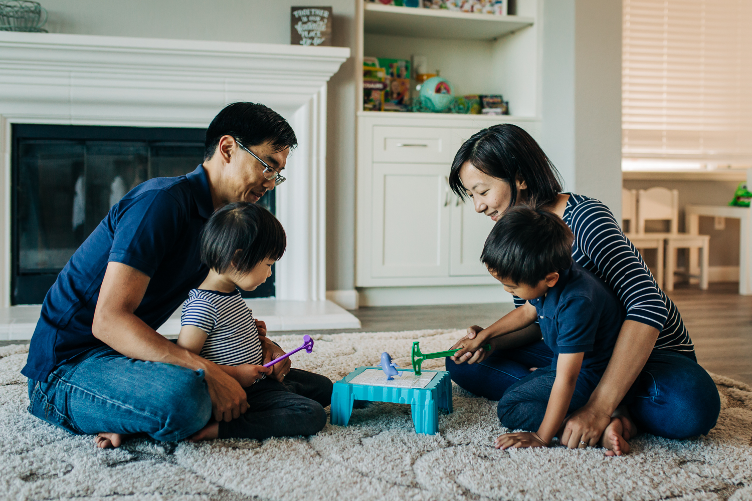 family of four sitting on the floor playing a board game together | East Bay Lifestyle Photographer