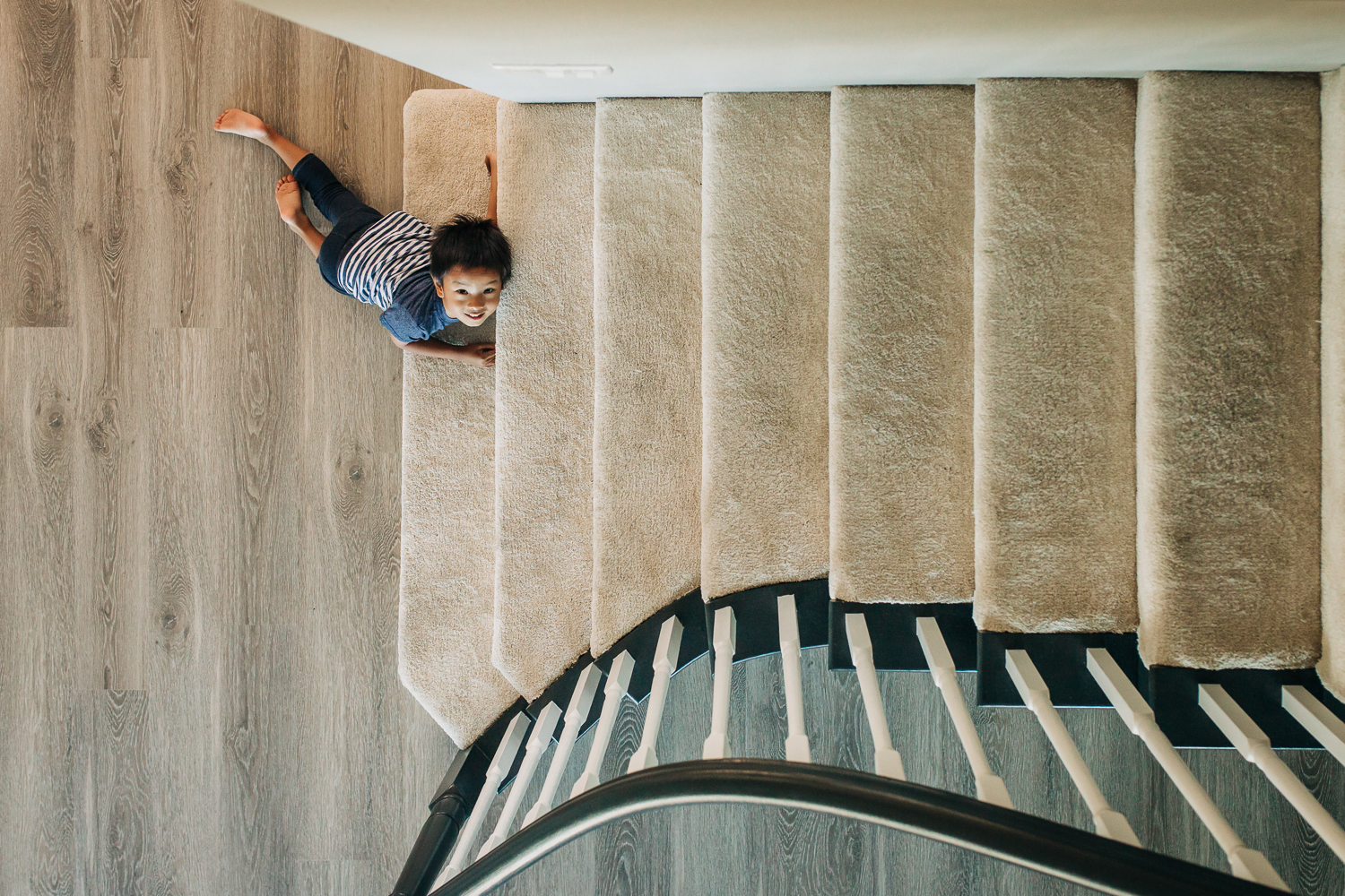 birds eye view of four year old boy as he lays at the bottom of the steps | East Bay Lifestyle Family Photographer