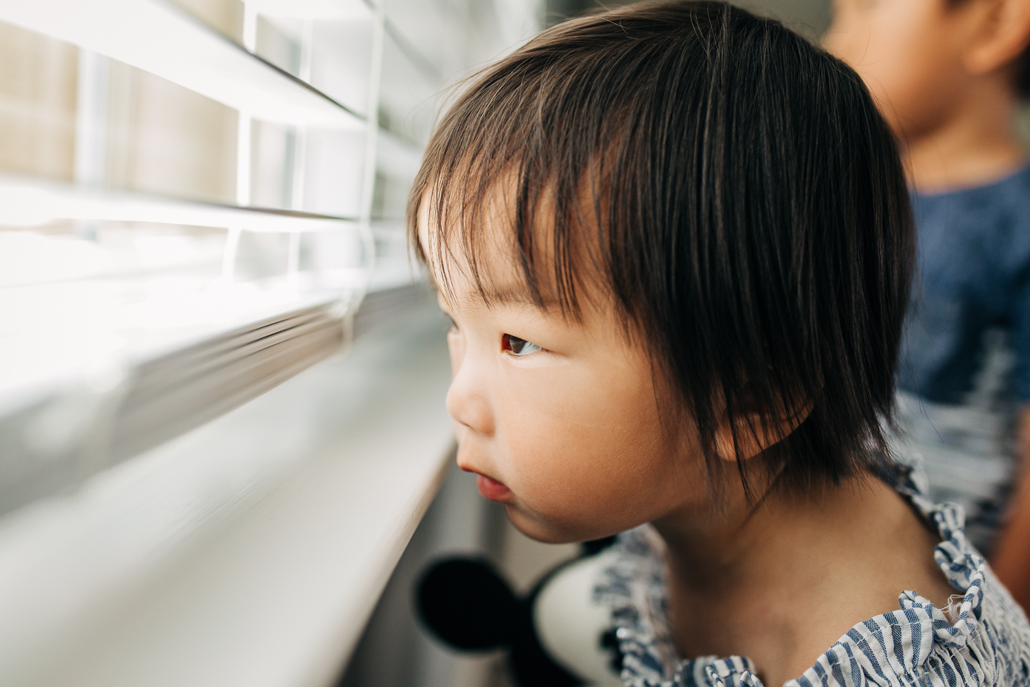 2 year old girl looking out blinds in a window {East Bay in-home lifestyle family photographer}