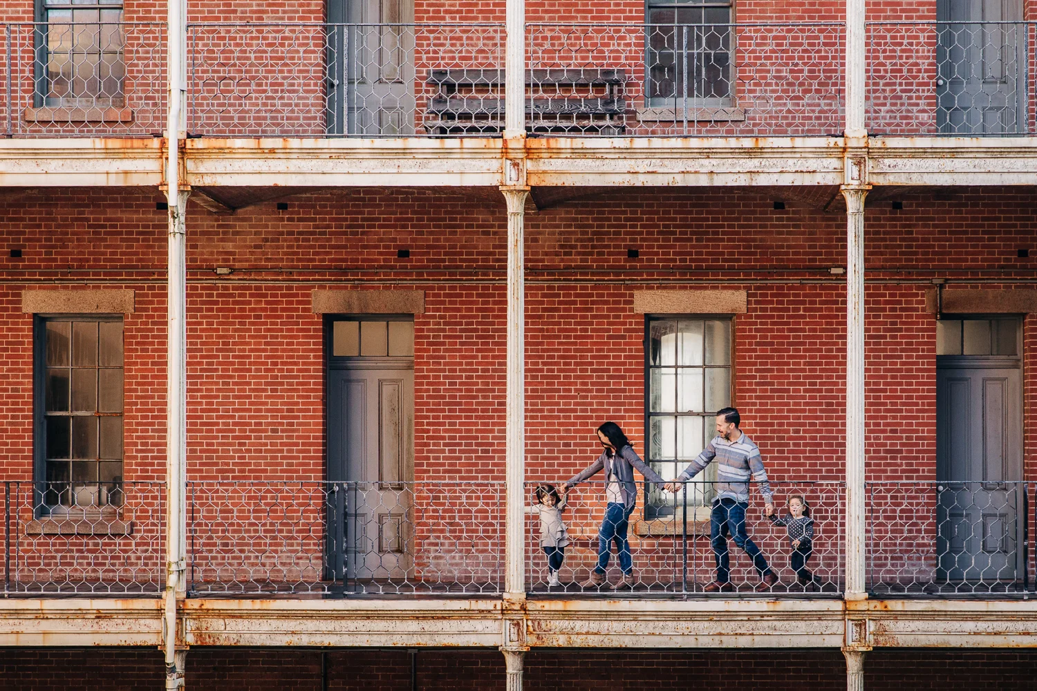family walking and holding hands in front of a brick building | San Francisco Family Photography
