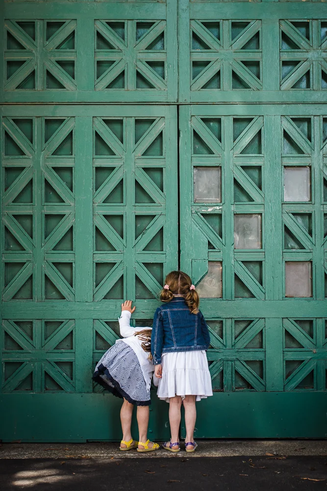 sisters standing in front of large green doors - san francisco child photographer