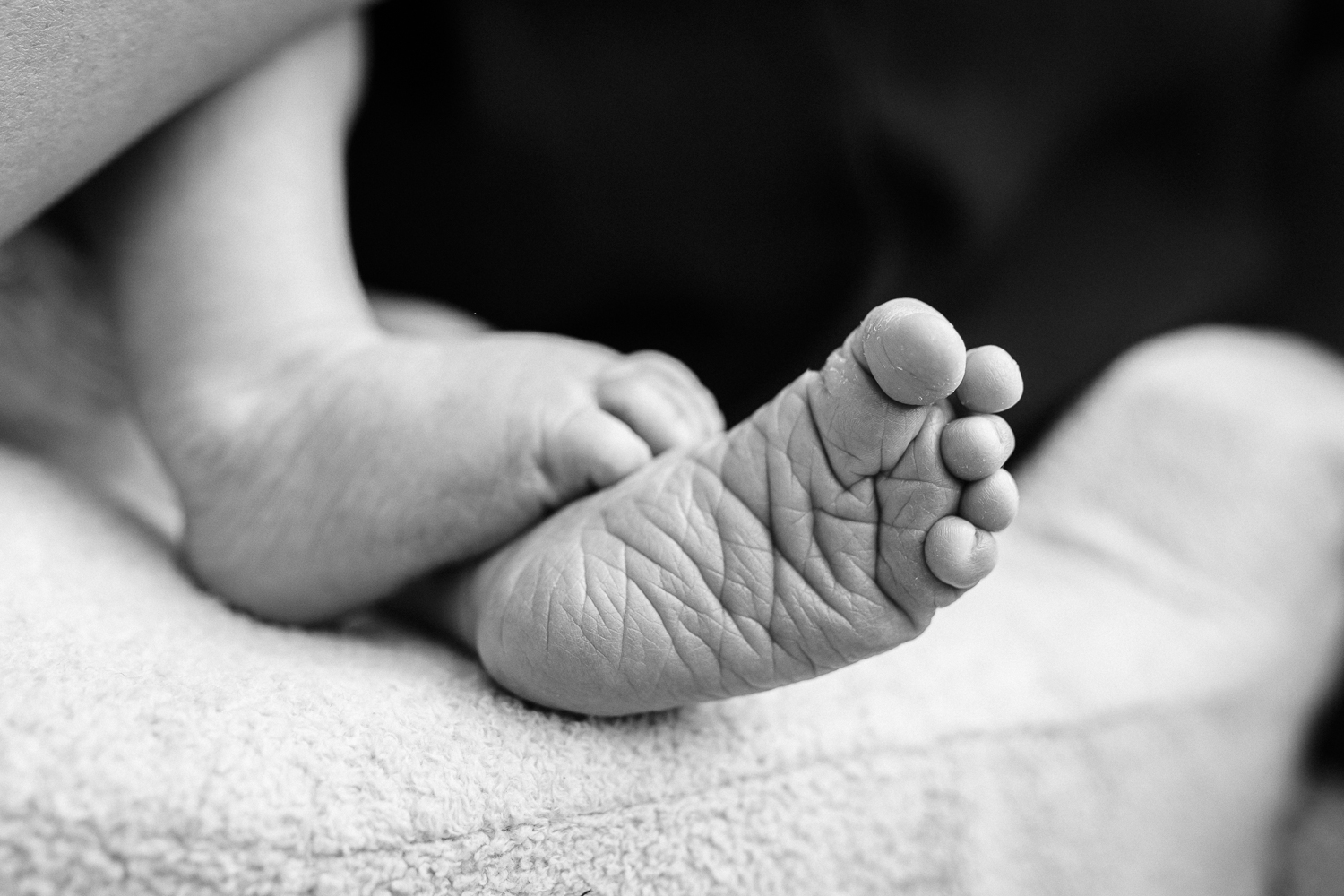 black and white shot of baby feet while a mother nurses | San Francisco Baby Photography