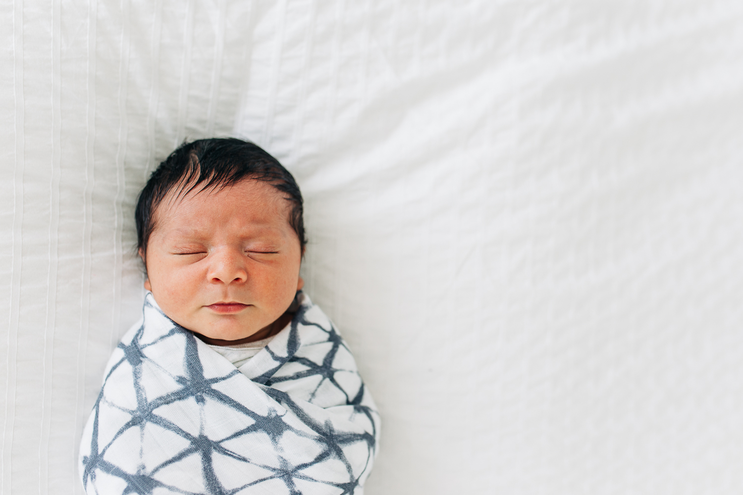 swaddled newborn baby boy sleeping on a white comforter | San Francisco Baby Photographer