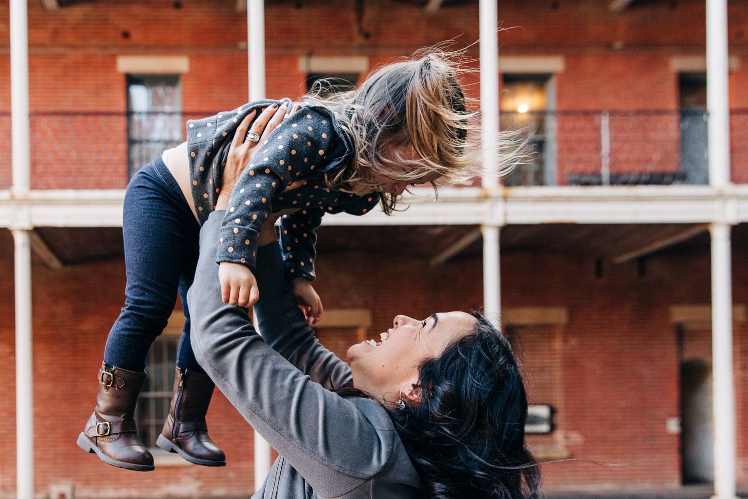 Mother holding up her two year old girl and they are looking into each other's eyes and smiling {San Francisco Family Photography}