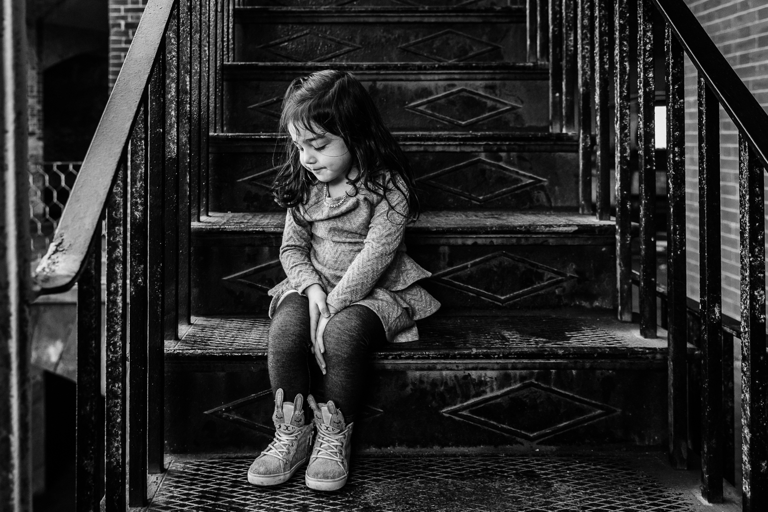 black and white photo of a four year old girl sitting on stairs and looking down {San Francisco Family Photographer}