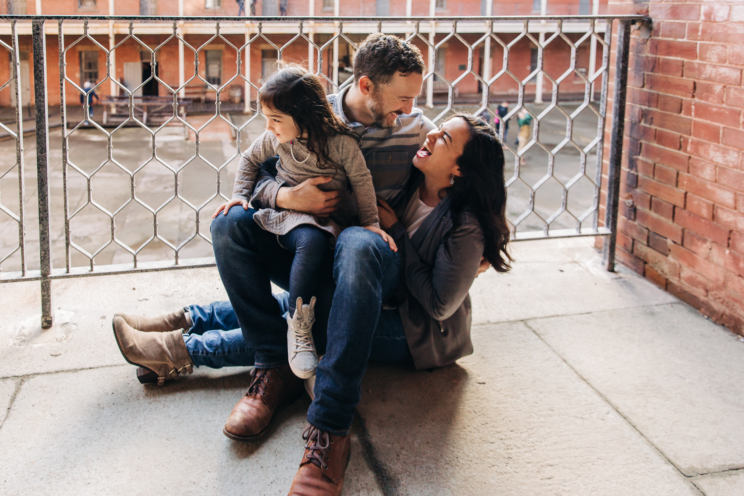 Family sitting on the ground together with mom and dad looking at each other and laughing {San Francisco Lifestyle Photographer}