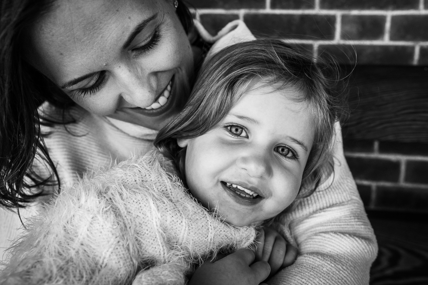 black and white close up photo of a mom looking down and smiling at her two year old daughter who is looking at the camera {Bay Area Photographer}