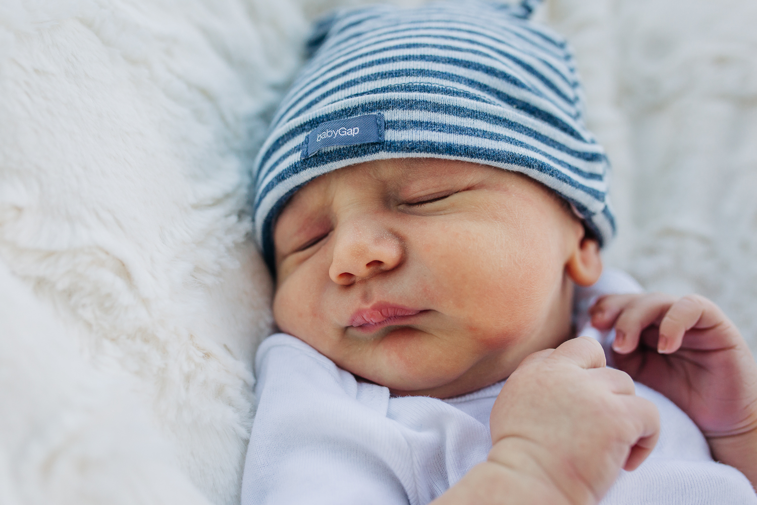 Close up of a newborn boy as he sleeps in a striped blue hat | Bay Area Baby Photographer