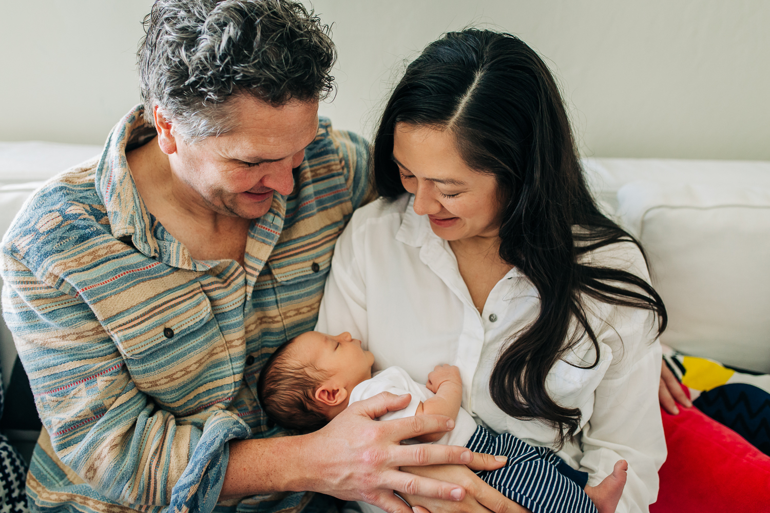 A new mother and father holding and looking down at their one week old baby boy | San Francisco Newborn Photographer