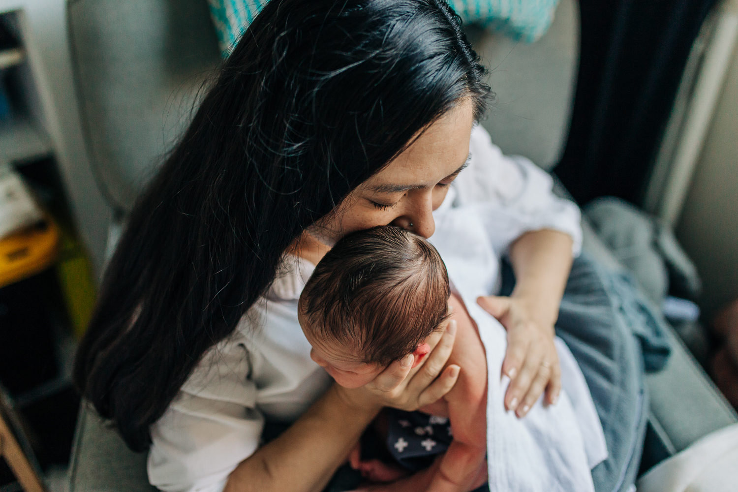 Mother holding and kissing her newborn boy as she burps him | San Francisco Baby Photographer