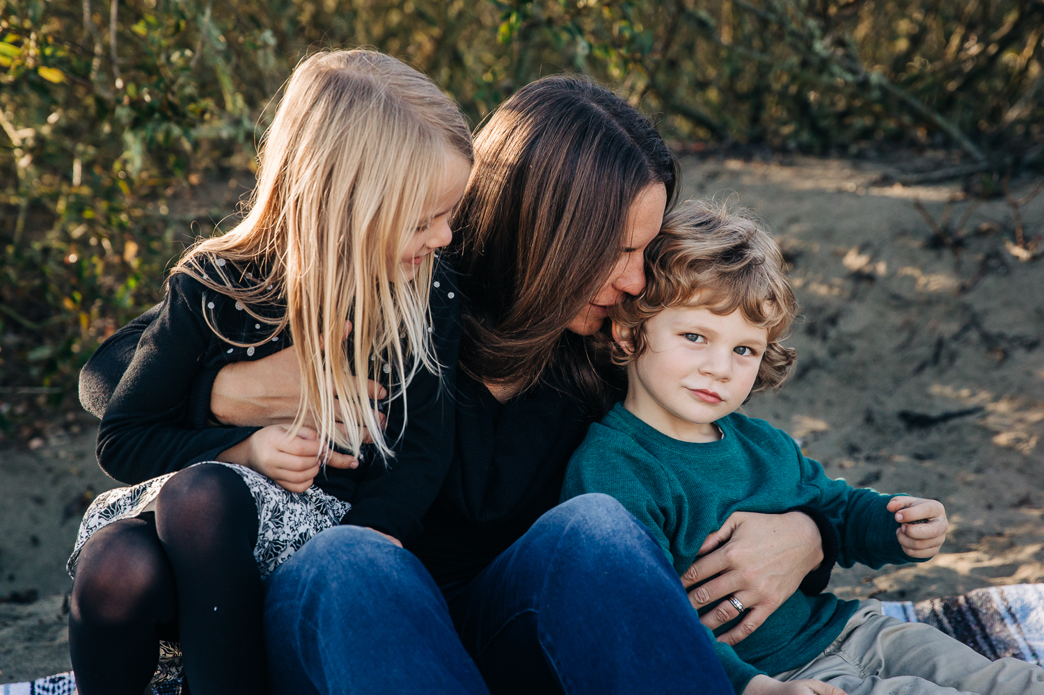 mom sitting on a blanket and snuggling her two small children and her son looks right at the camera | SF Bay Area Family Photography