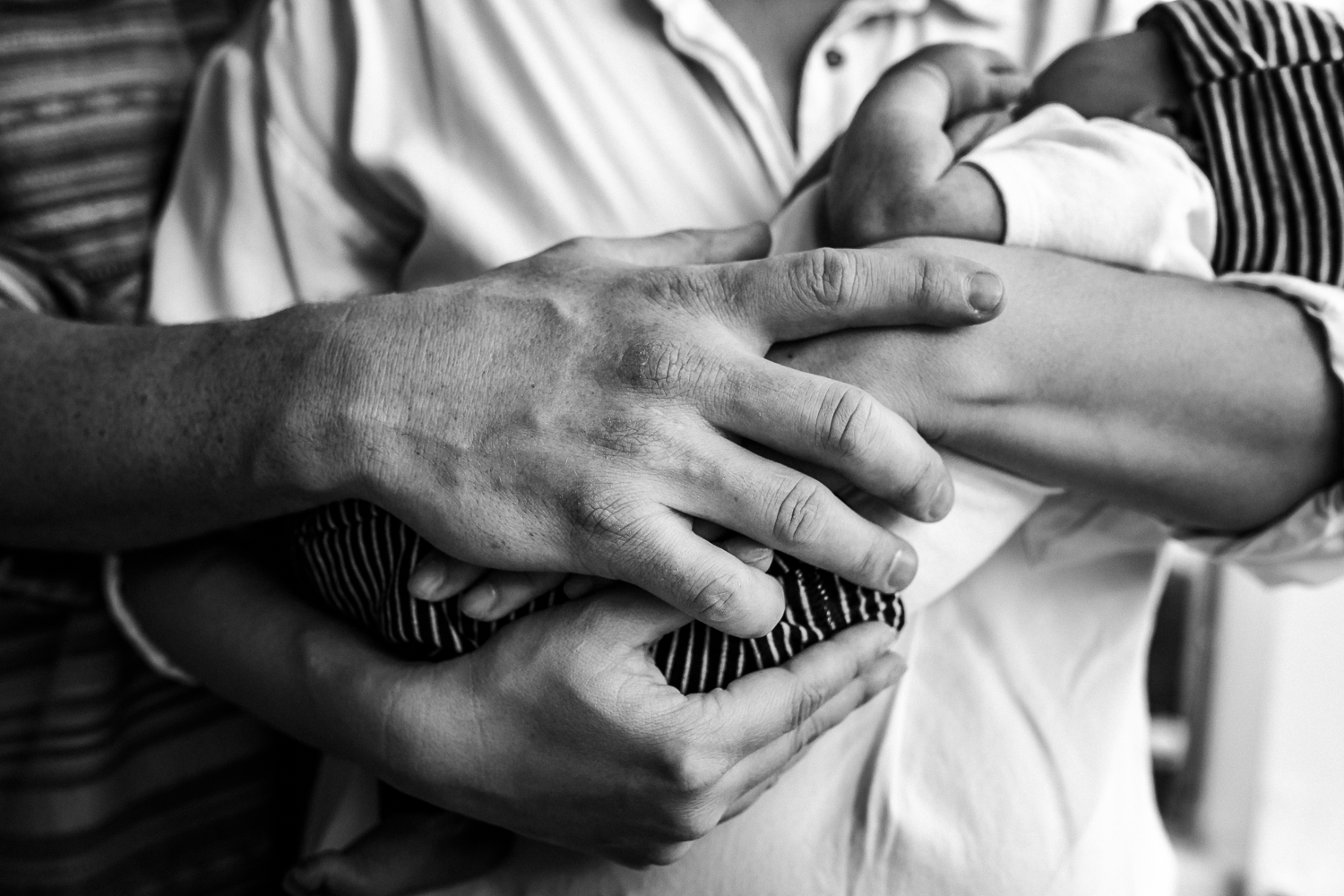 black and white photo of mom and dad holding hands and their newborn baby boy | Bay Area Newborn Photography