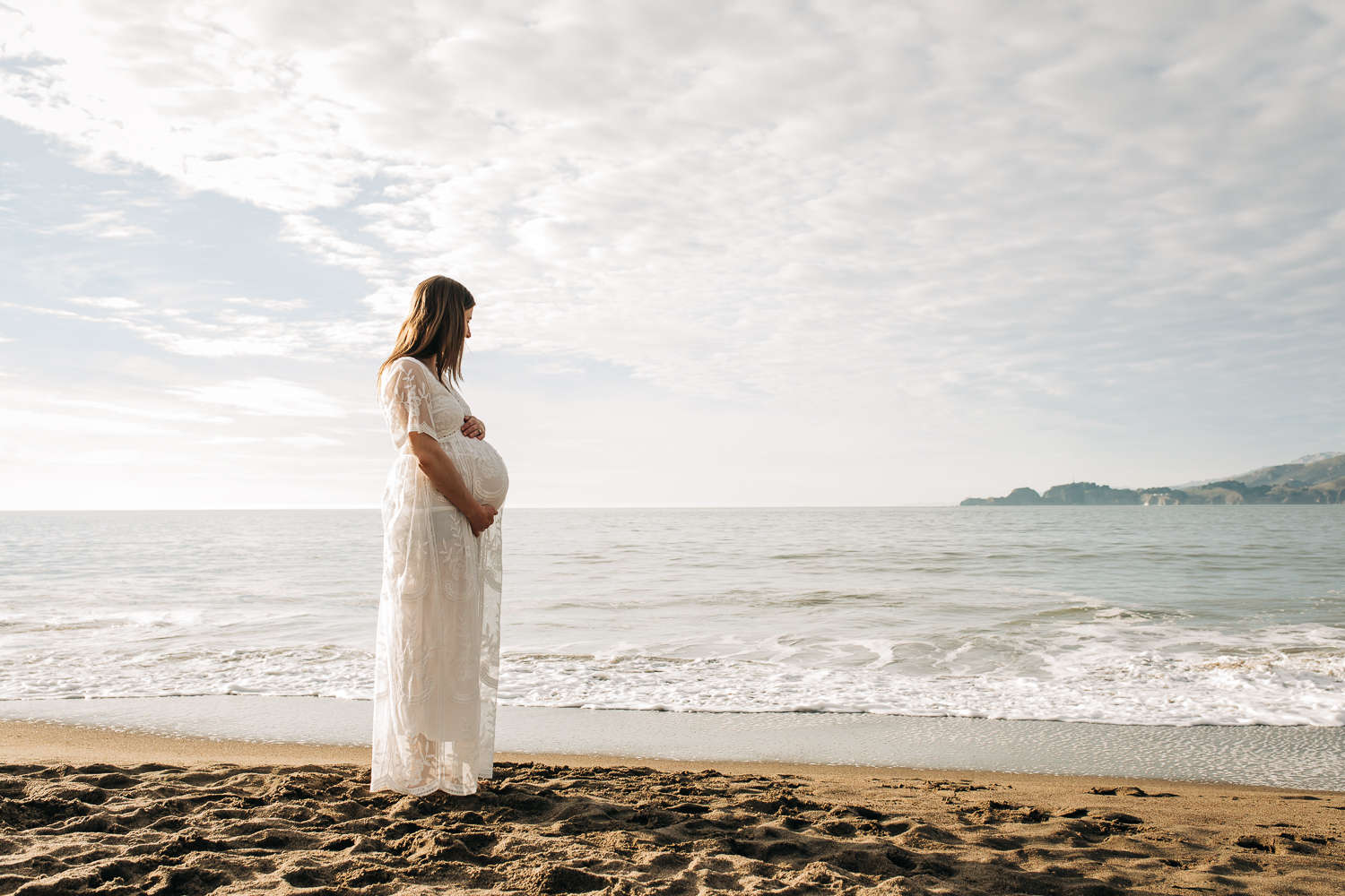 Profile portrait of pregnant mother standing on the beach and looking out at the ocean | San Francisco Maternity Photography