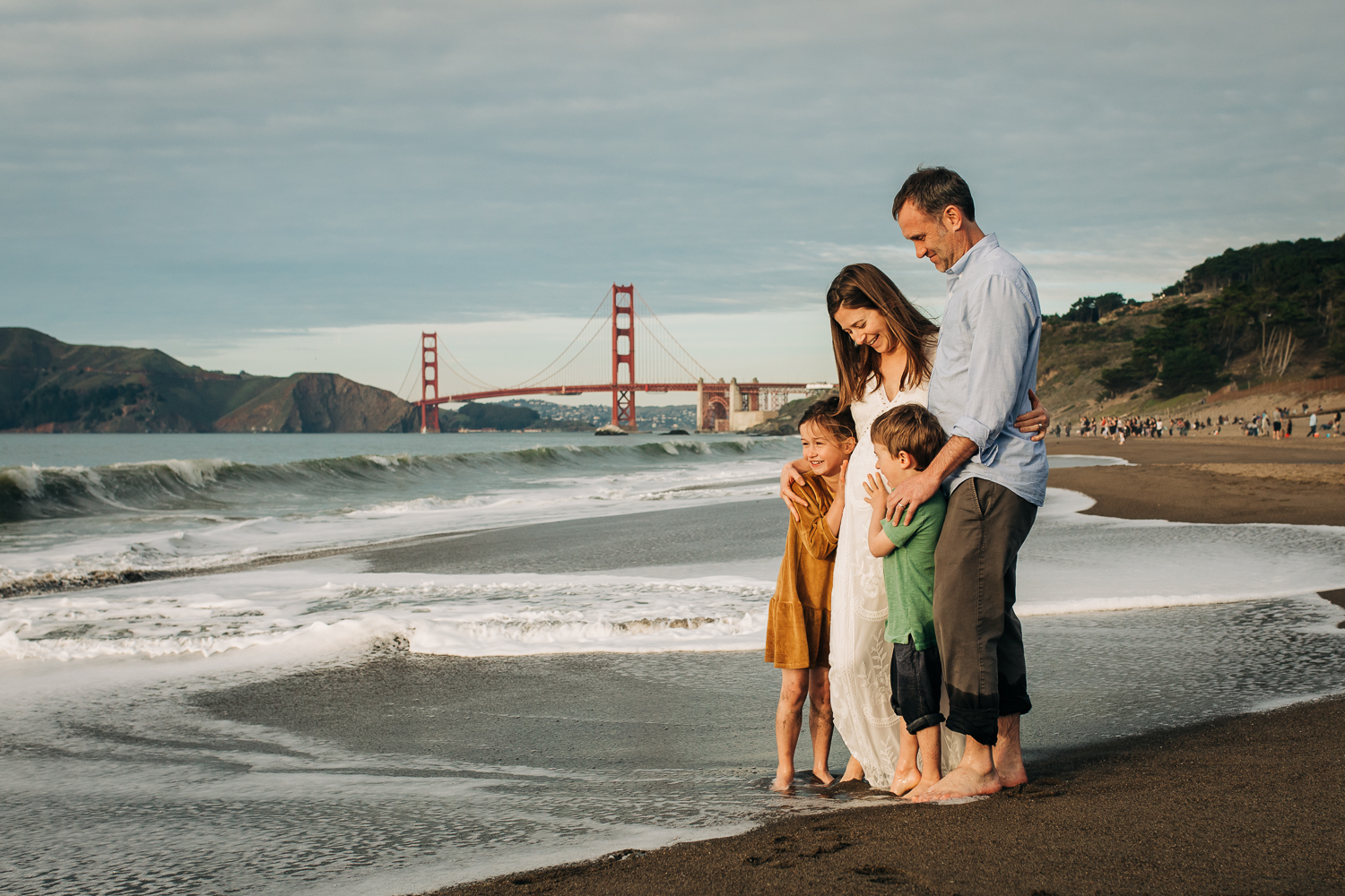 Family Portrait of a boy and a girl with both parents standing at Baker beach with the Golden Gate Bridge in the background | San Francisco Family Photography