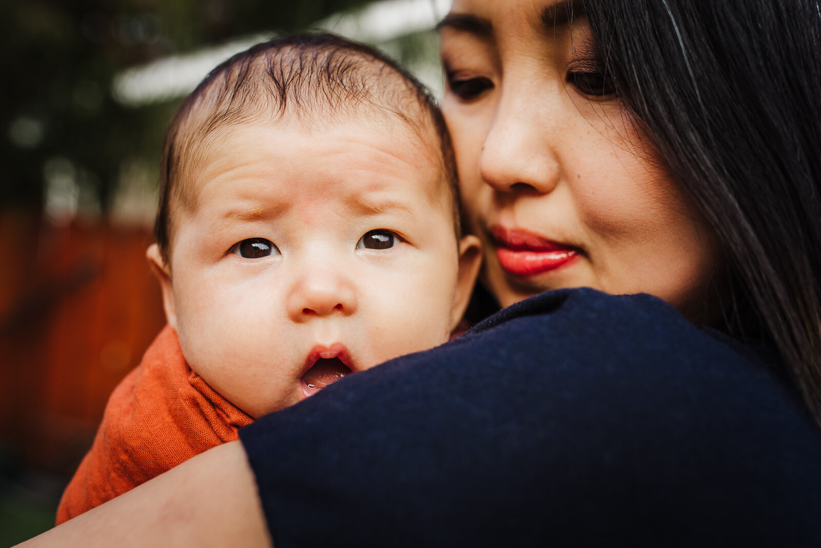 mom holding and snuggling baby as he looks at camera - Oakland Newborn Photographer