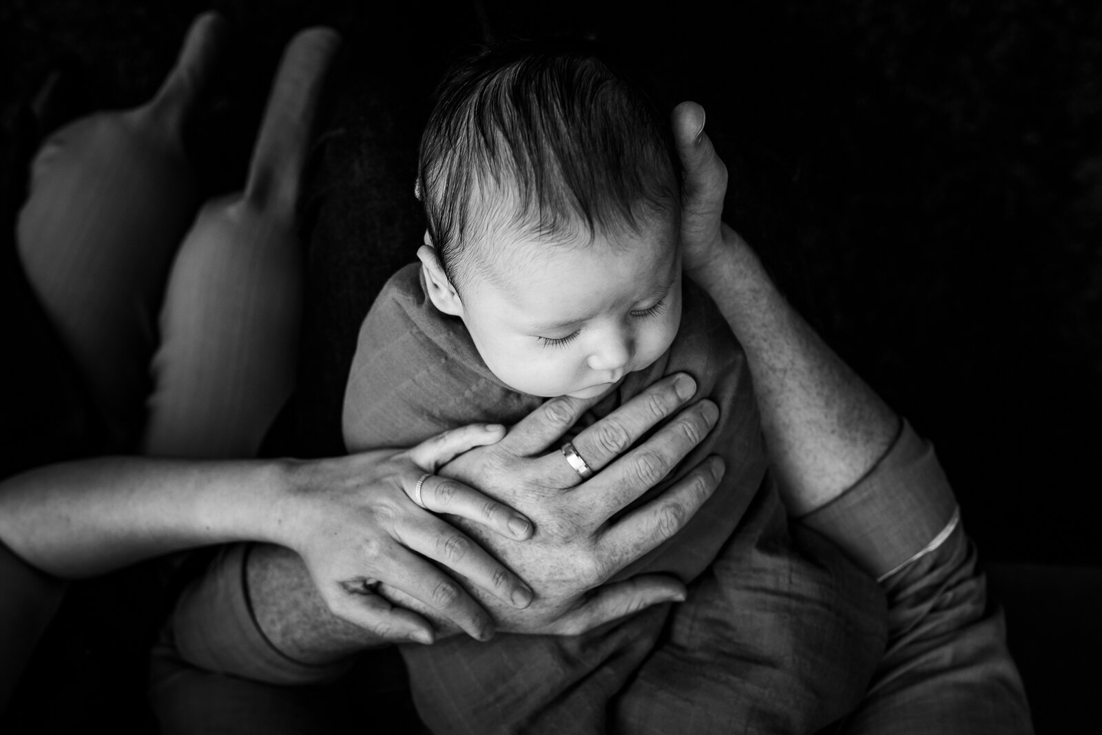 birds-eye view of baby boy in dad's arms with mom's hand touching him - Oakland Newborn Photographer