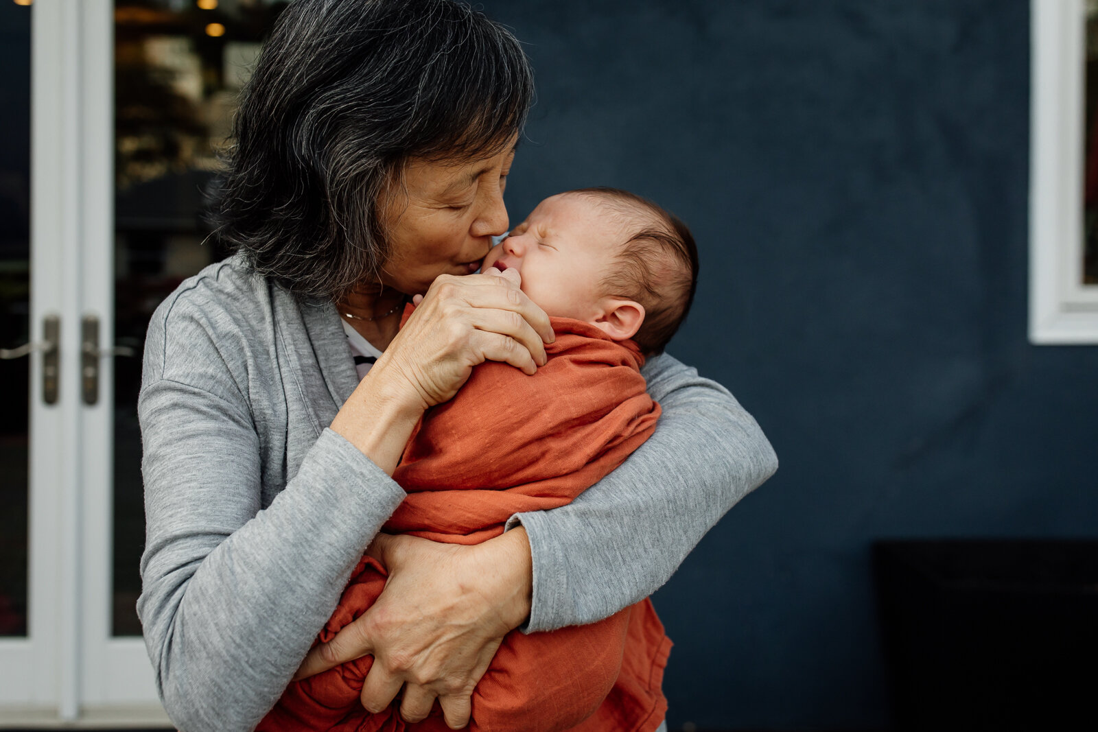grandmother holding and comforting baby grandson as he cries - East Bay Newborn Photographer 