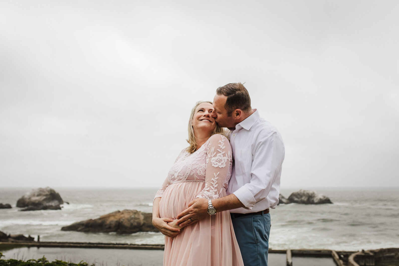 partner standing behind and hugging wife while they both hold her baby bump - San Francisco Maternity Photographer