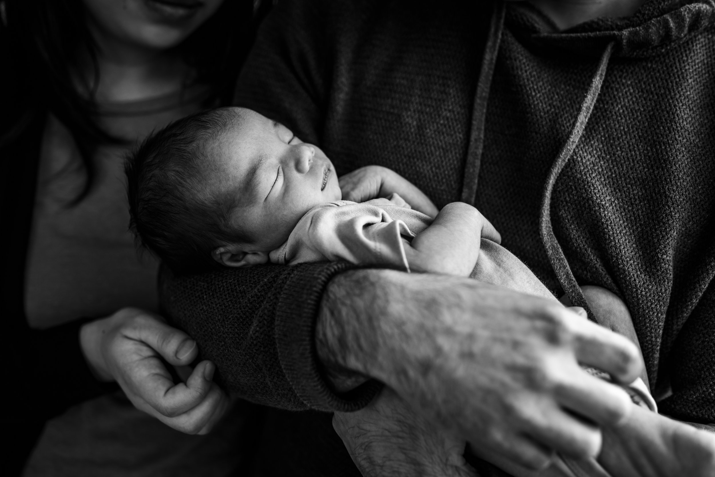 black and white profile of newborn sleeping in dad's arms