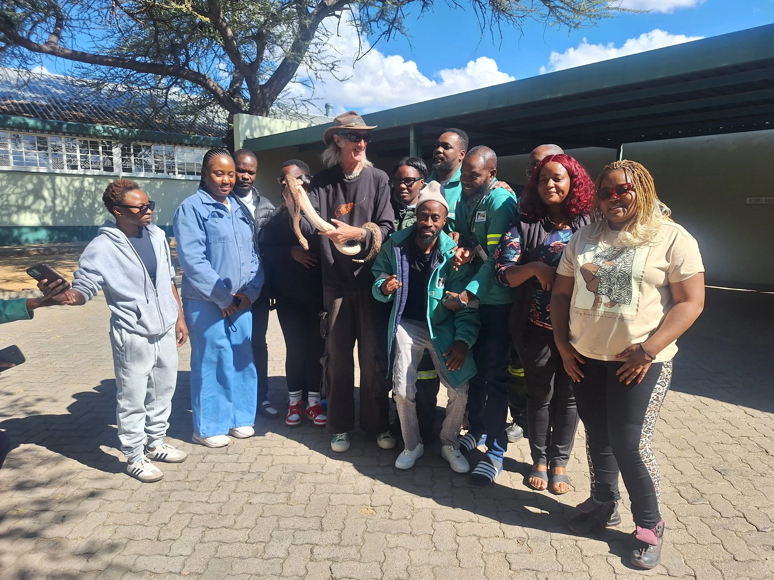 A group of snake handling trainees gather around for a group photo with an Anchieta's dwarf python after completing the course.