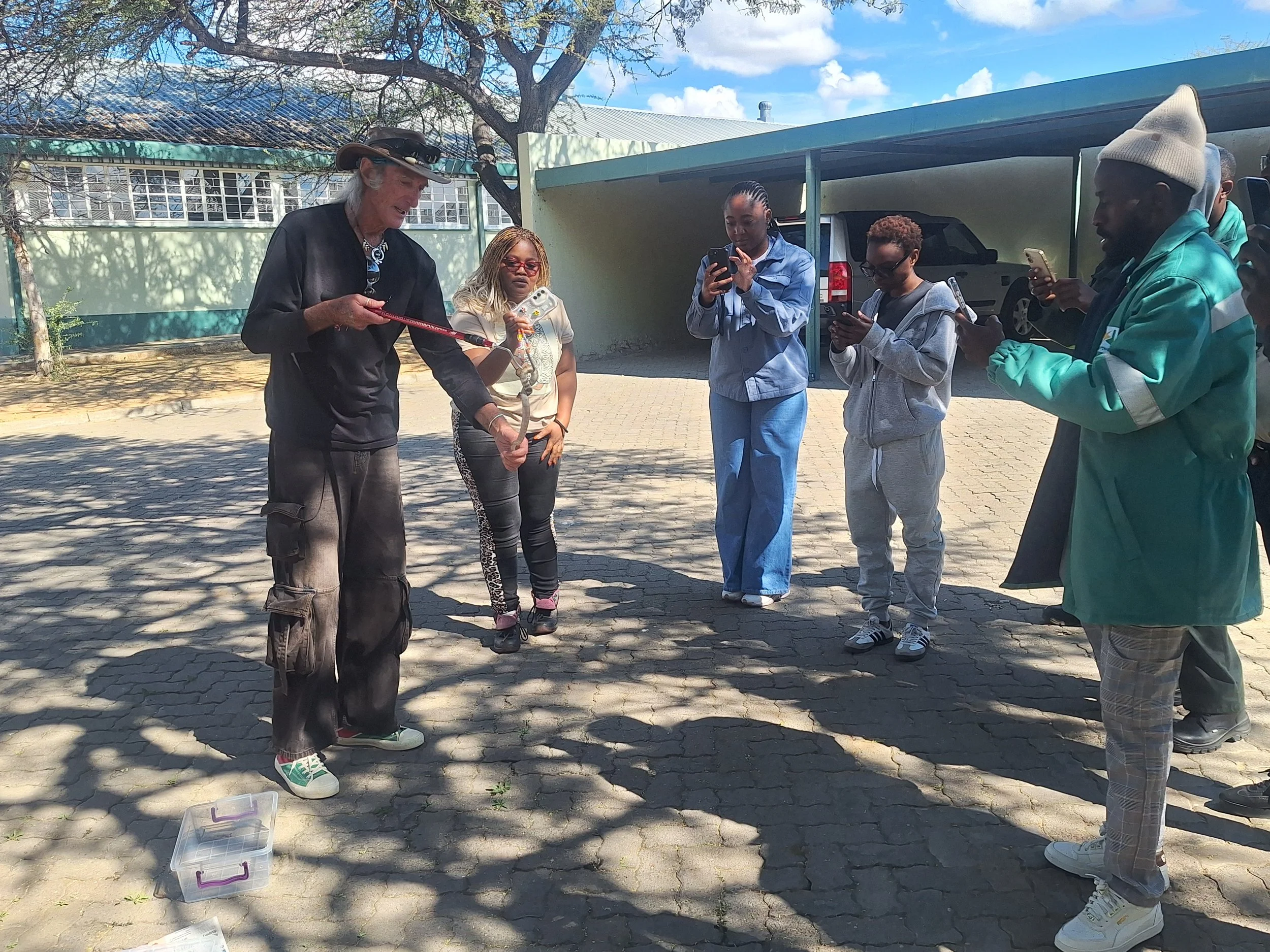 Group of snake handling trainees filming videos of how to safely catch and remove a snake from an animal human conflict situation. Snake conservation at grass roots level.
